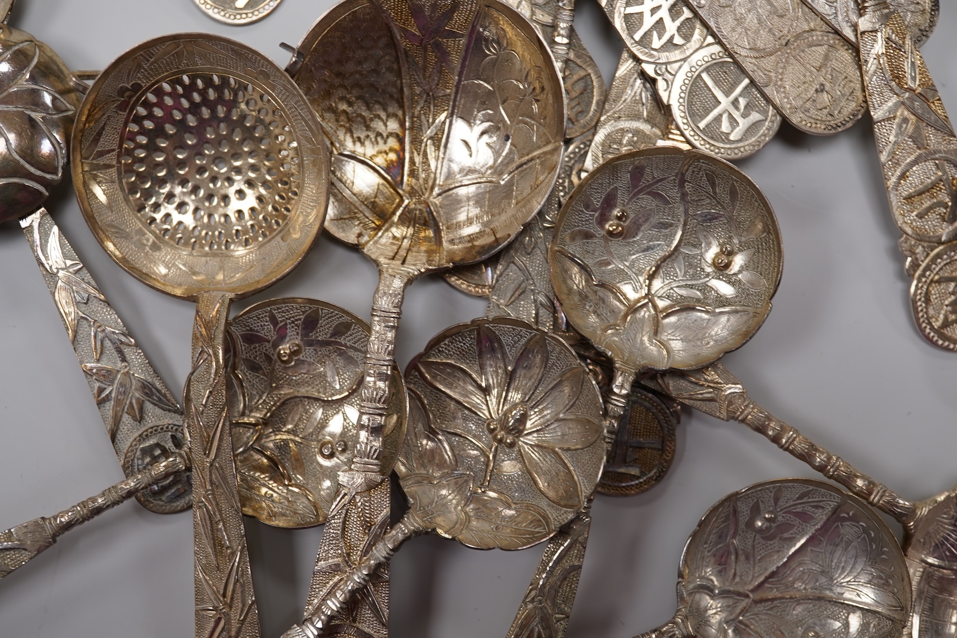 A set of twelve early 20th century Chinese Export white metal small spoons, maker LS, decorated with foliage and character mark, 10cm, a set of ten similar larger spoons, same maker, 12.3cm and another set a six similar